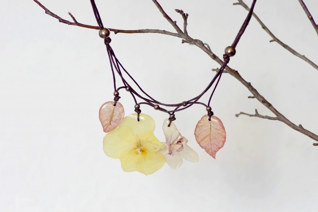 Quatre pendentifs végétaux, fleurs couleur pastel :2 bougainvillées, une pensée jaune et une orchidée. Tour de cou en coton noué, perles en inox.
