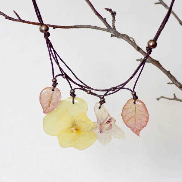 Quatre pendentifs végétaux, fleurs couleur pastel :2 bougainvillées, une pensée jaune et une orchidée. Tour de cou en coton noué, perles en inox.