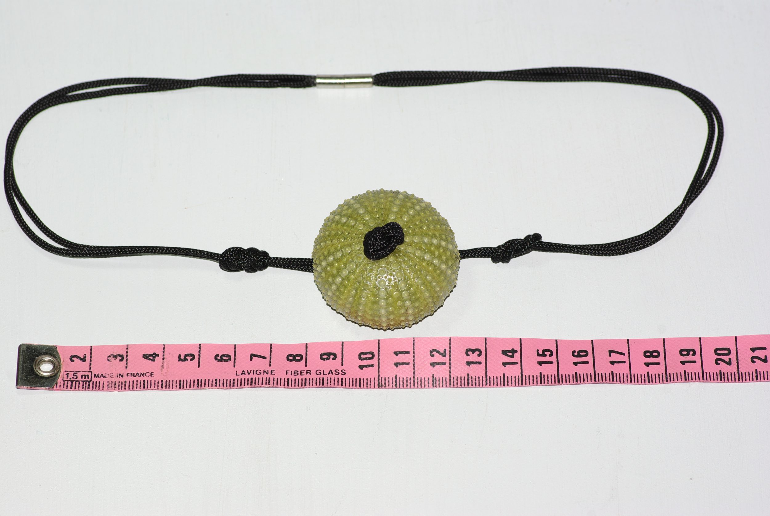 Collier avec un pendentif oursin vert sur une cordelette noire en polyester nouée façon marine. mesures
