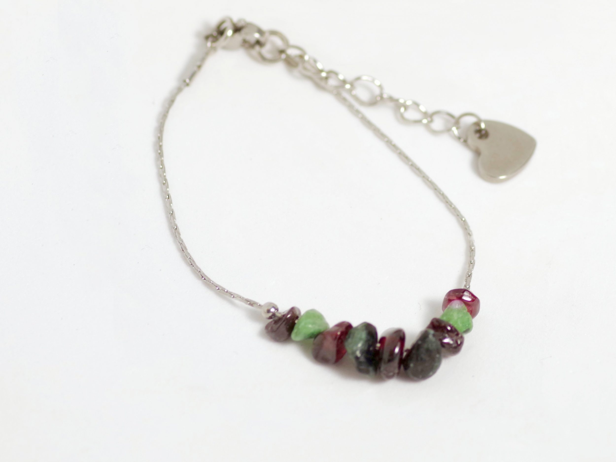 bracelet réglable,chaîne très fine en inox, quelques perles de pierres gemmes veres et rouges, coeur en inox au bout de la chaînette du fermoir