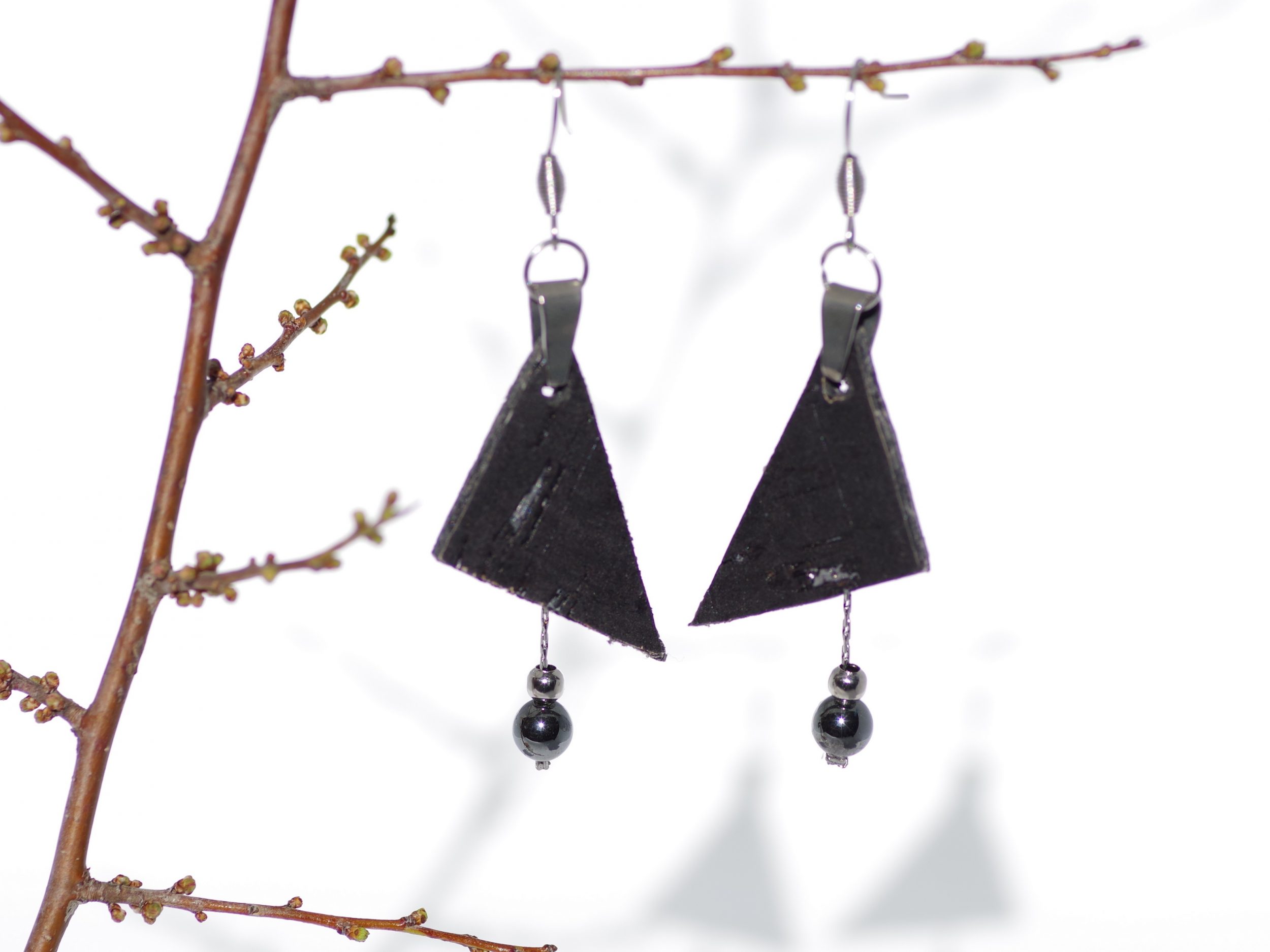 Boucles d'oreilles avec deux pendentifs : un triangle de liège noir et argent et une chaîne argentée portant des perles noires