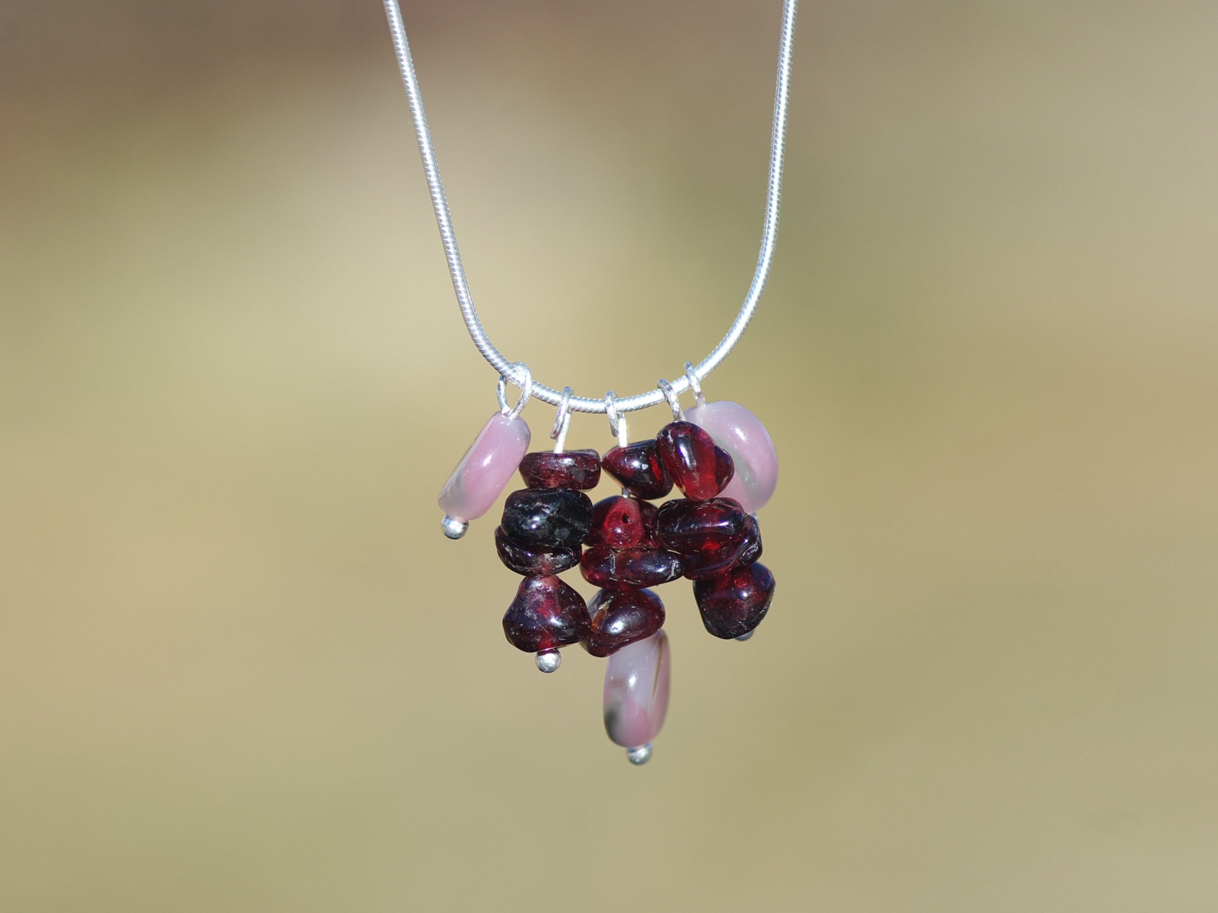 Fine chaîne serpentine avec un pendentif gemmes.Grenats presque bruts et des perles d'opales roses.