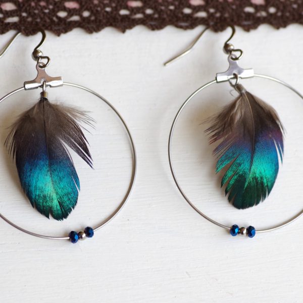 boucles d'oreilles à plumes bleues aux reflets brillants dans des anneaux argentés agrémentés de trois petites perles assorties aux plumes