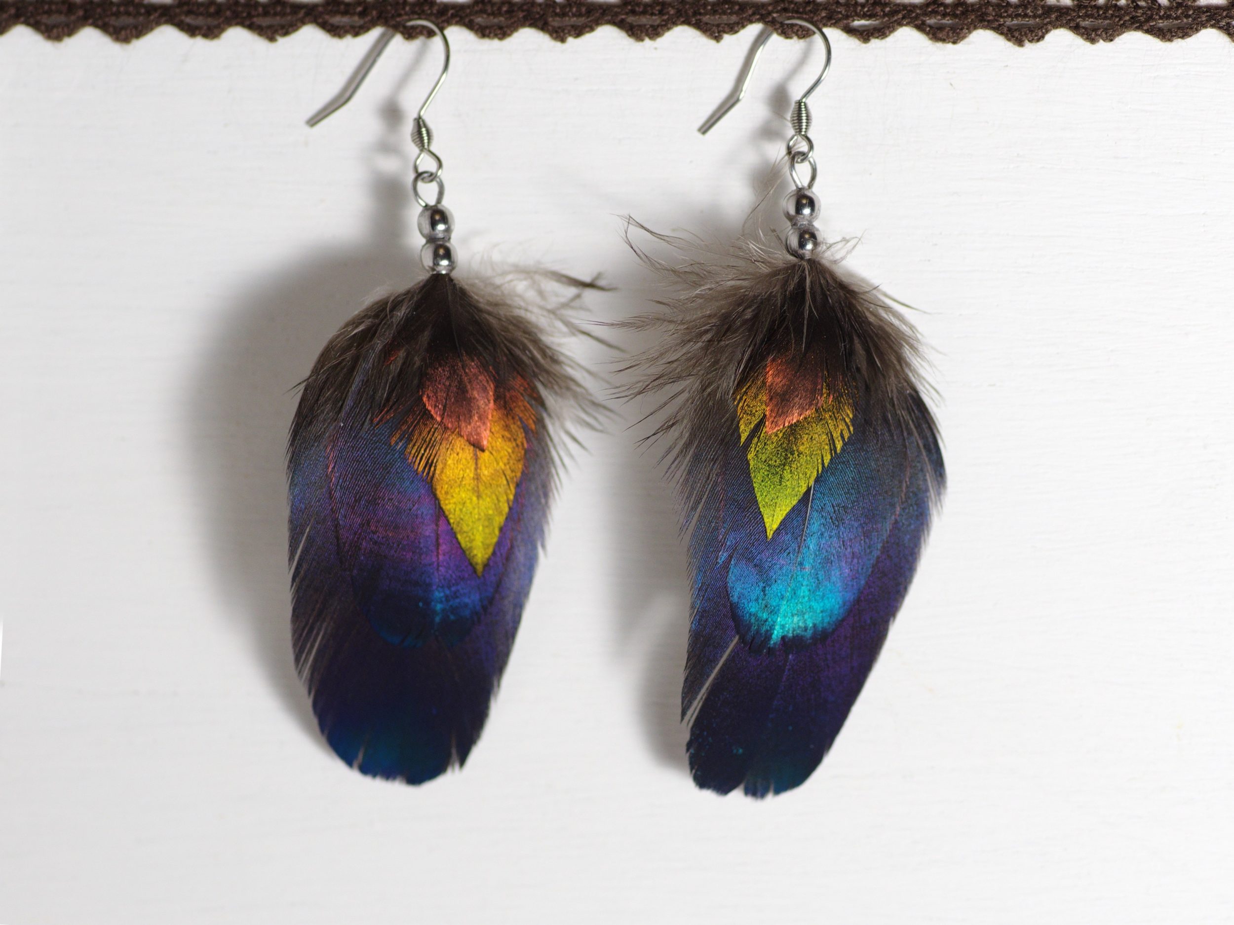 boucles d'oreilles plumes multicolores et brillantes : 4 plumes superposées par ordre de taille : pette plume triangulaire cuivrée, plume triangulaire verte, deux plumes ovales bleues avec des reflets turquoise