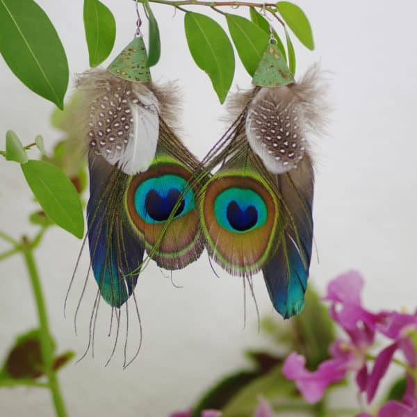 grandes boucles d'oreilles au style ethnique: composition avec oeil de paon associé à une grande plume bleue et des plumes blac et gris à pois blancs