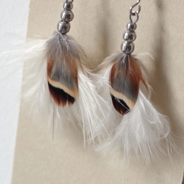 boucles d'oreilles en duvet blanc formant un petit pompon, associé à une plume rayée gris marron et beige,le pendentif de plumes est maintenu par trois perles inox