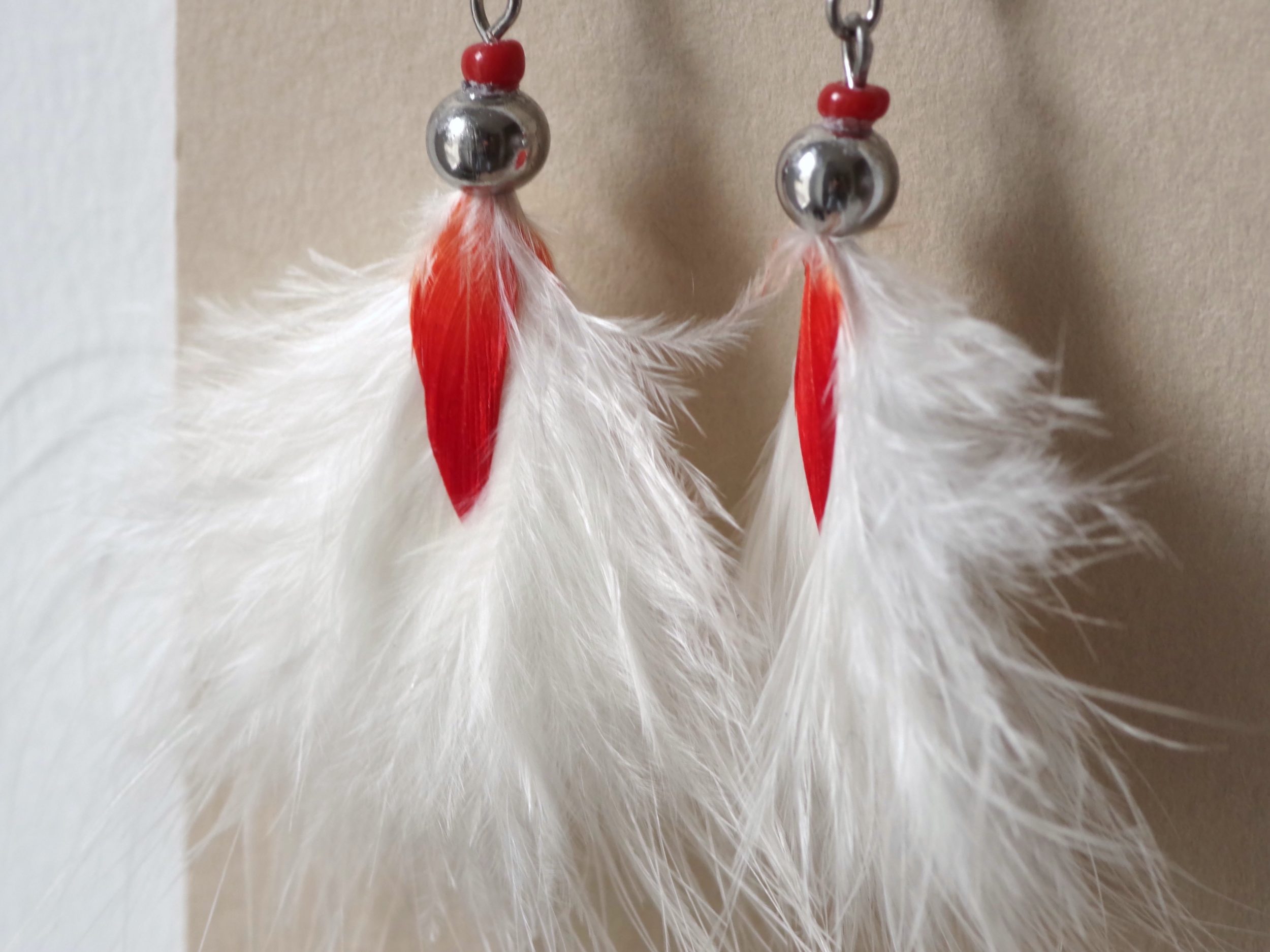 boucles d'oreilles rouge et blanc, plumes duveteuses très vaporeuses blanches disposées en pompon, avec une petite plume rouge au milieu