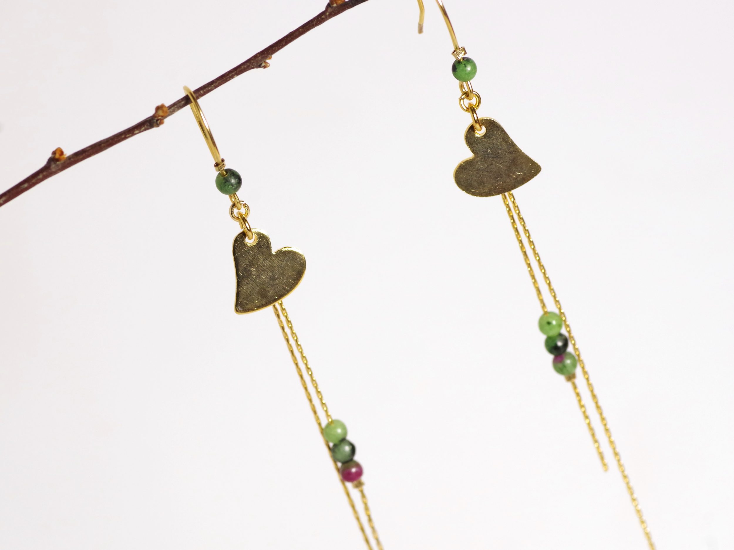boucles d'oreilles avec un petit cœur doré et des petites perles sur une fine chaîne dorée.