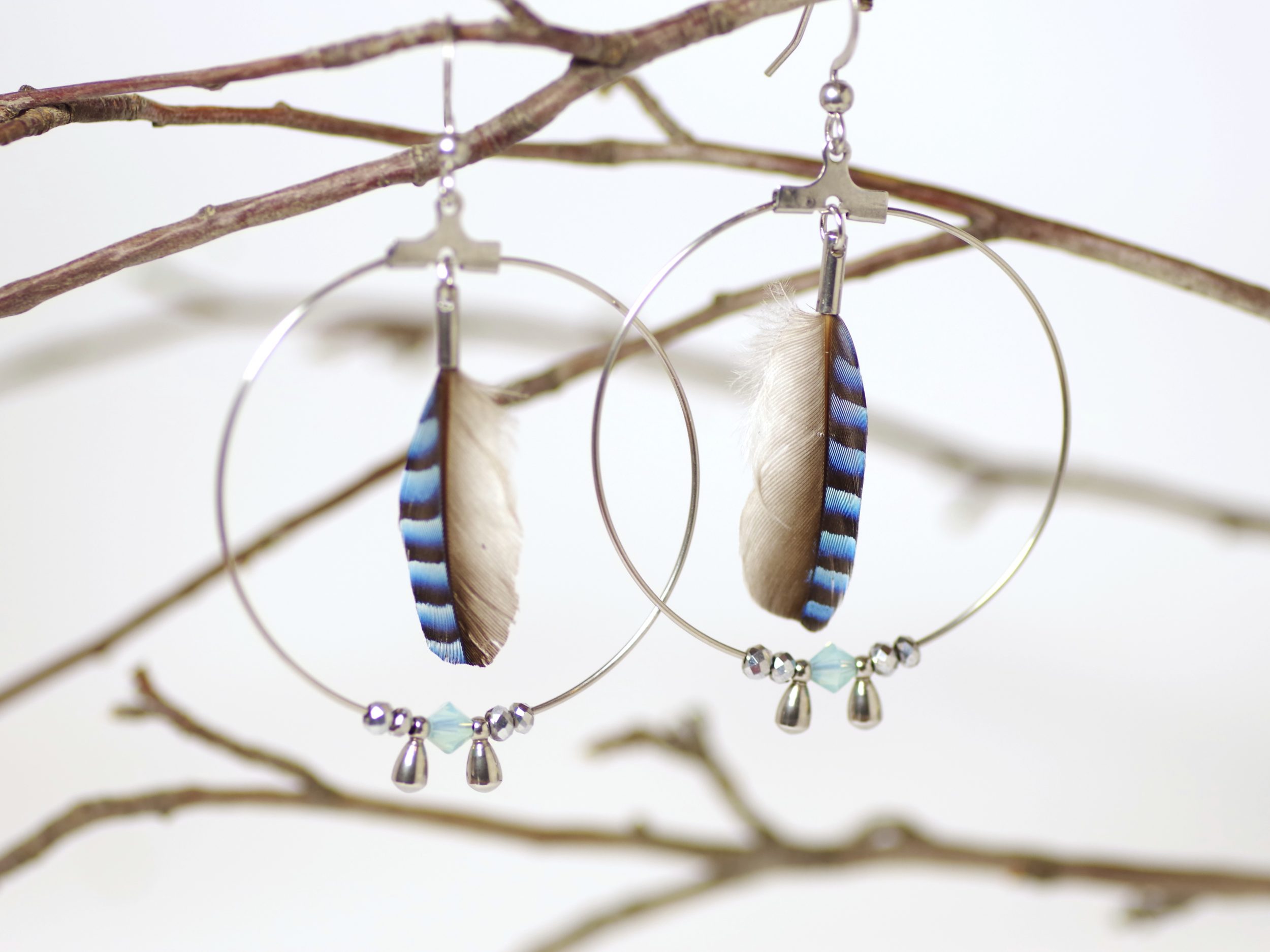 boucles d"oreilles avec grand anneau inox , plume bleue rayée et petites perles bleues et argentées.