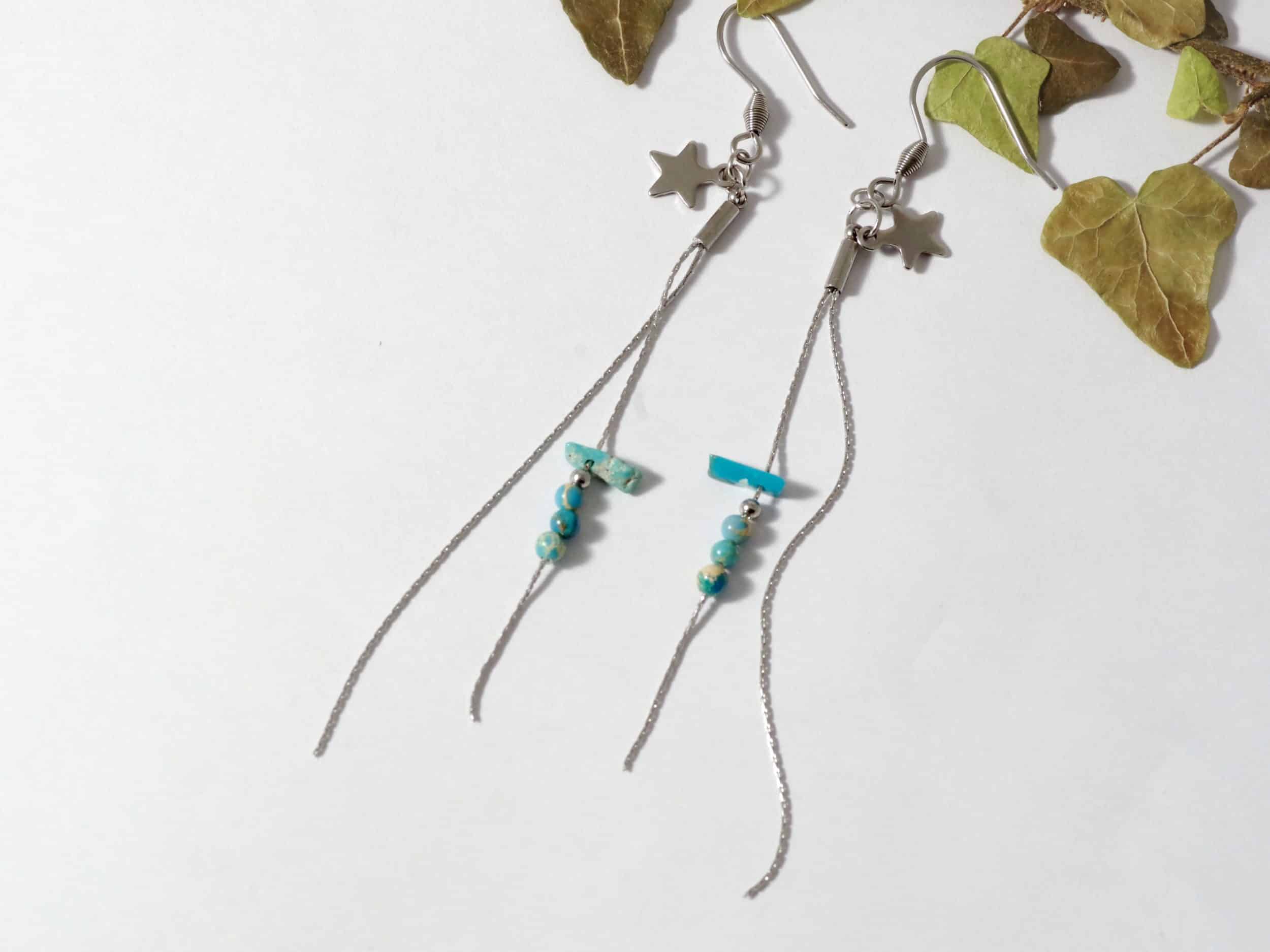 Boucles d'oreilles longues avec deux chaines fines, une étoile et des perles de pierre turquoises. Inox