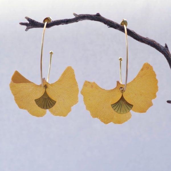 feuilles de ginkgo jaunes en boucles d'oreilles sur des grandes créoles dorées