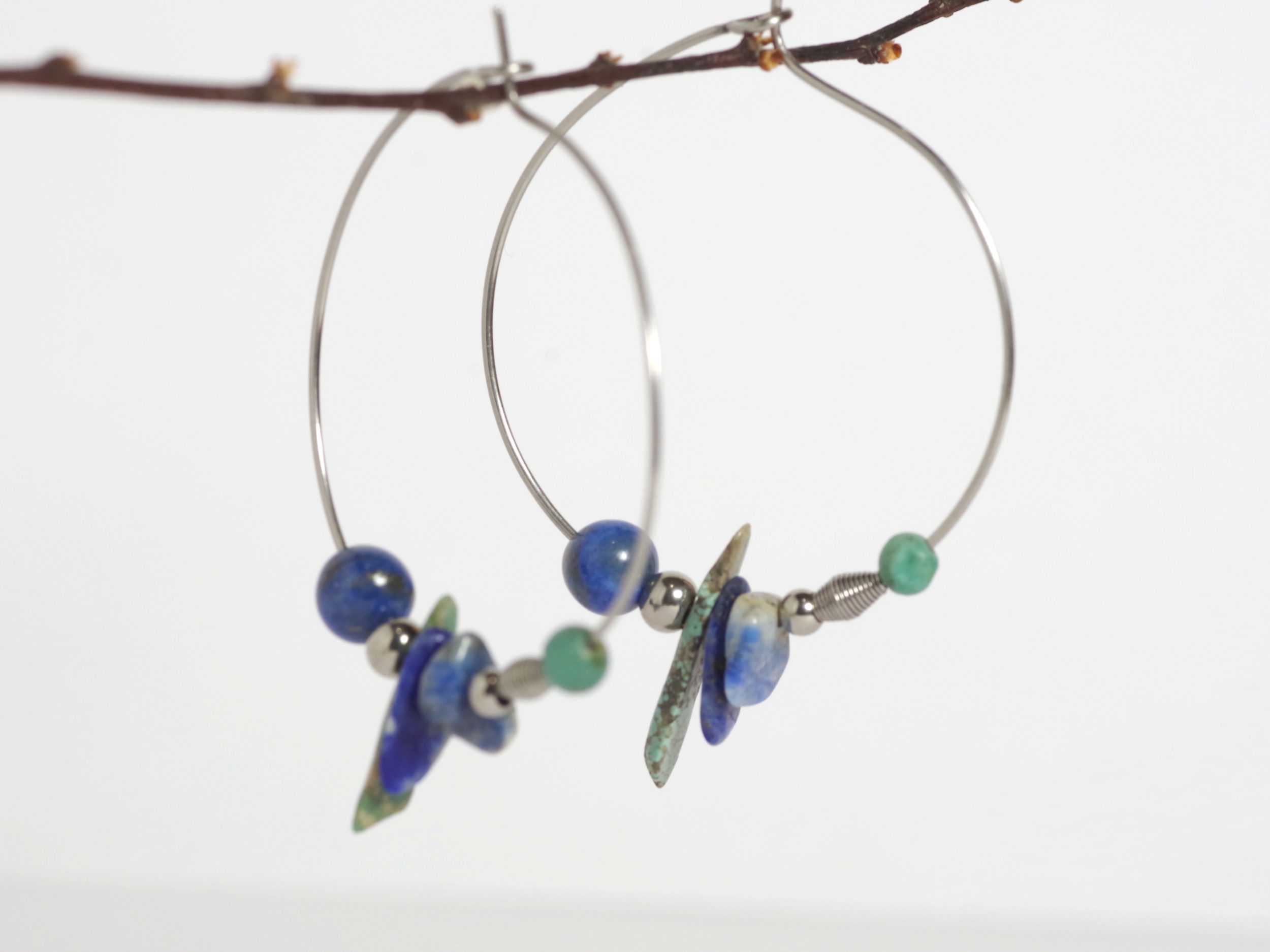 Boucles d'oreilles créoles avec des pierres bleues de formes et couleurs variées : mélange de turquoise et lapis lazuli. créoles en inox.