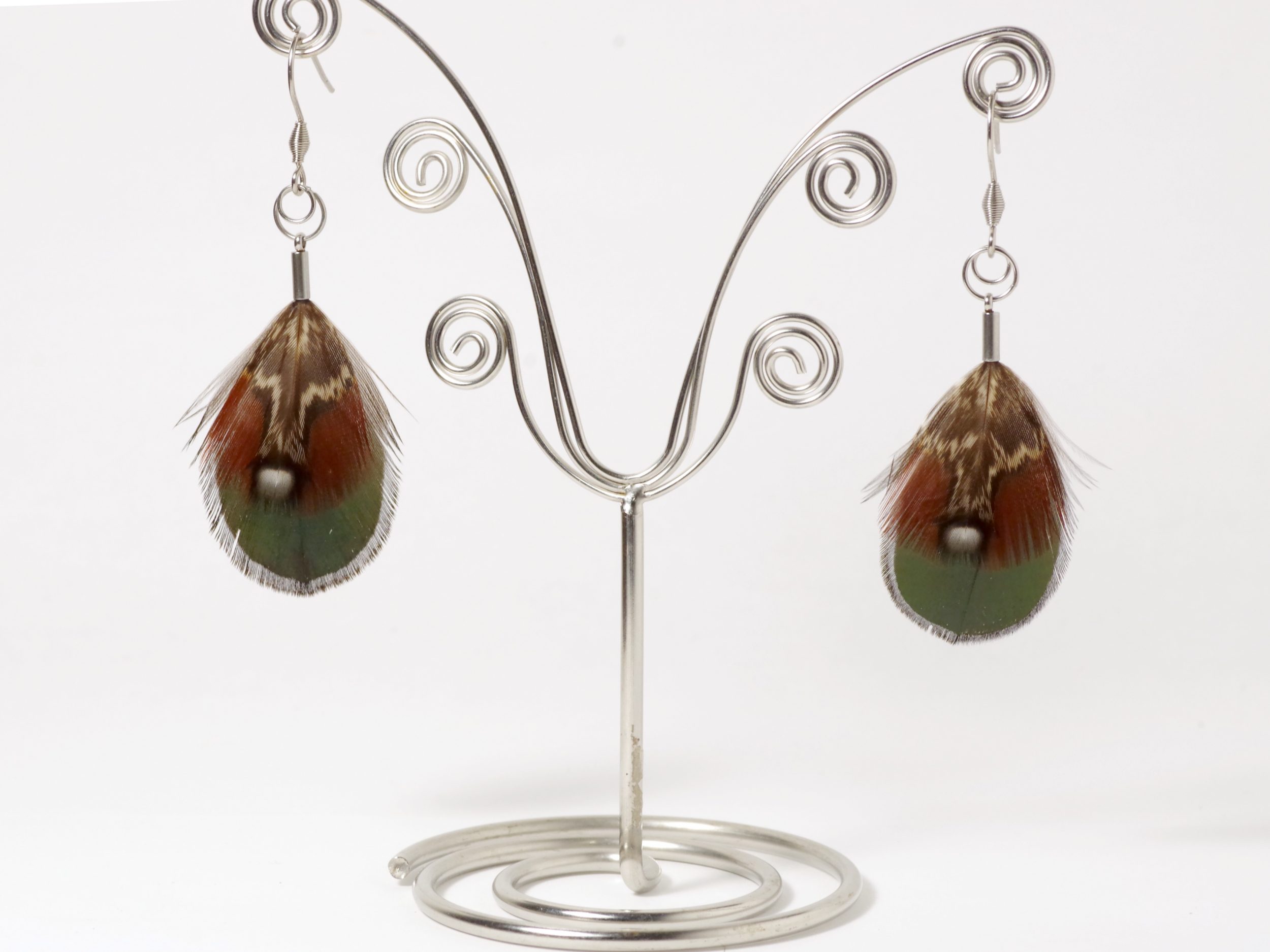 Une paire de boucles d'oreilles avec de petites plumes vertes et rousses avec des graphismes blancs et noir.