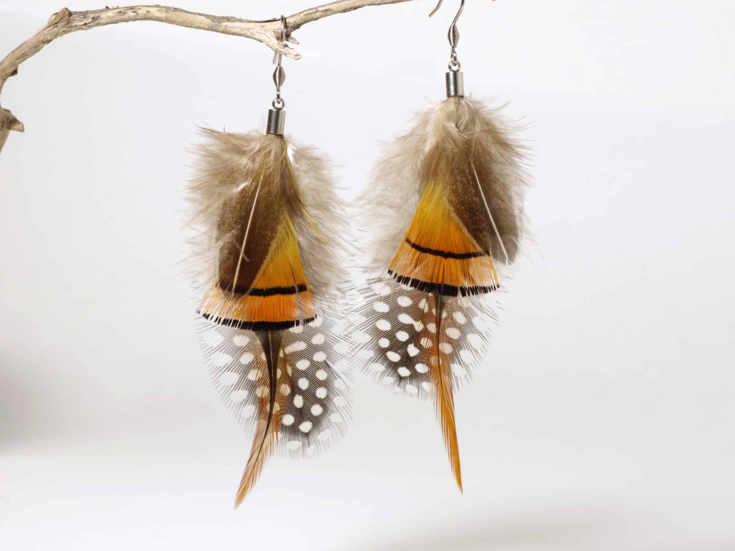 grandes boucles d'oreilles en plumes colorées et graphique, style nature sauvage. orange, brun et blanc