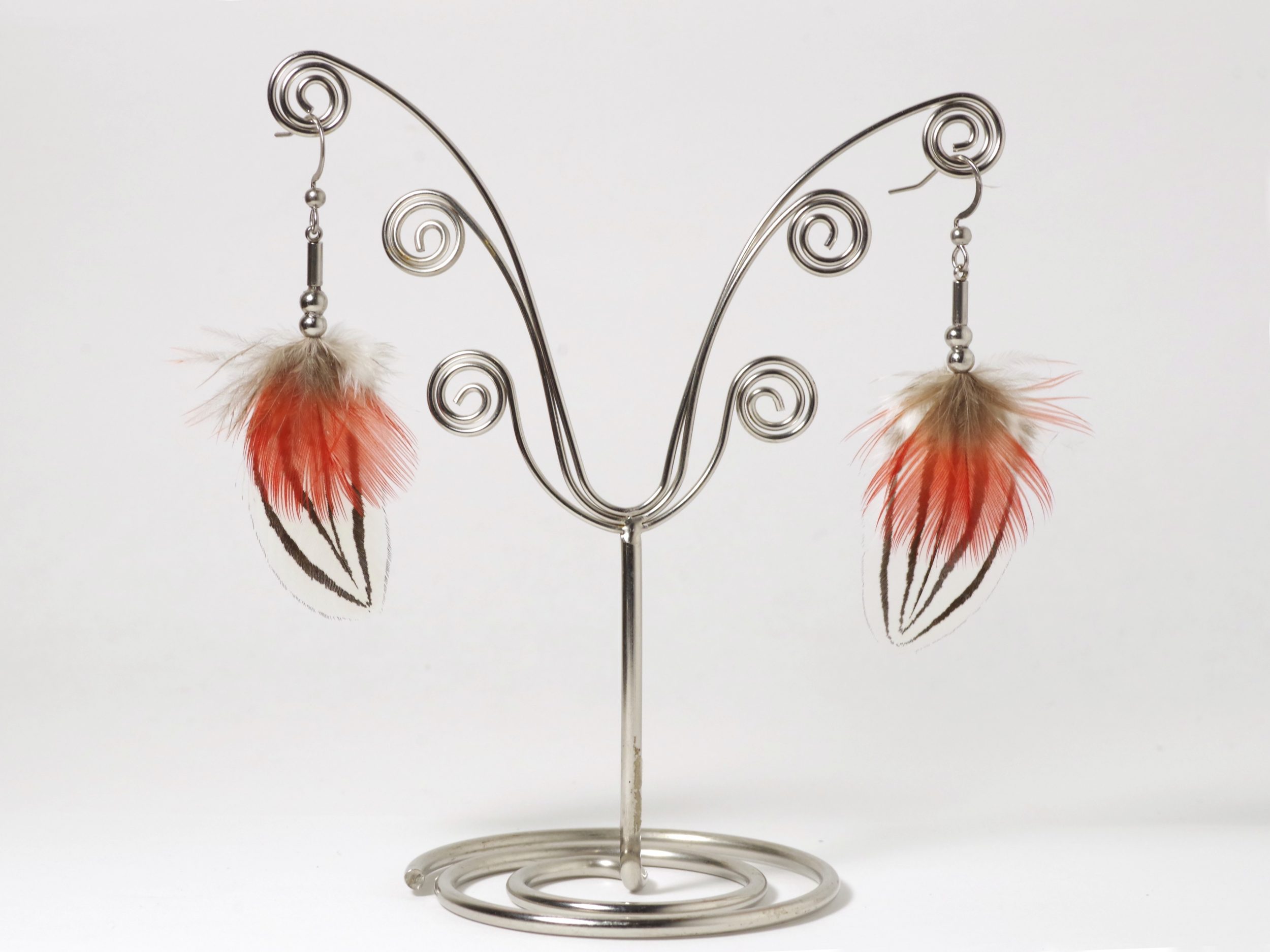 Une paire de boucles d'oreilles avec des plumes d'un rouge éclatant et des plumes blanches et noires