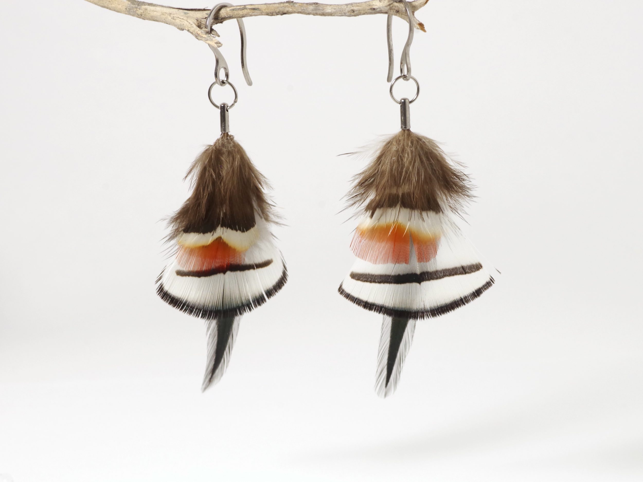 une paire de boucles d'oreilles avec une composition de plumes blanches et rouges et noires