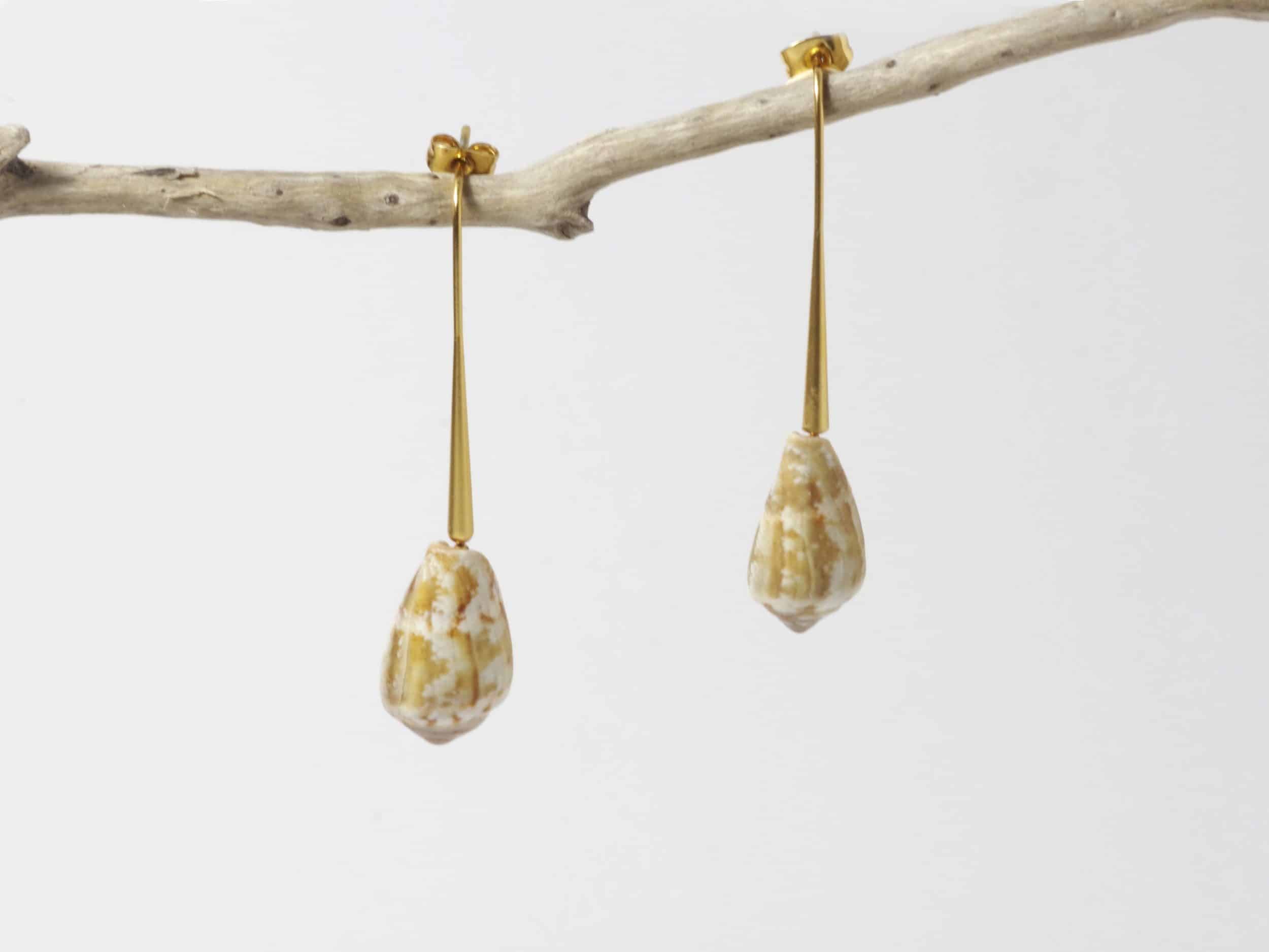 Boucles d'oreilles en coquillages stylés : des jolis coquillages en forme de cône prolongent une tige dorée au look épuré.