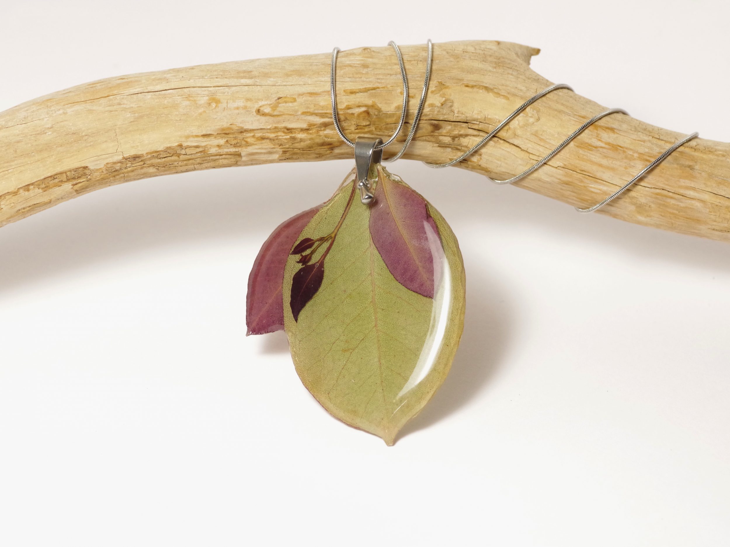 Un pendentif réalisé avec plusieurs feuilles d'eucalyptus, vert et rouge (pourpre)