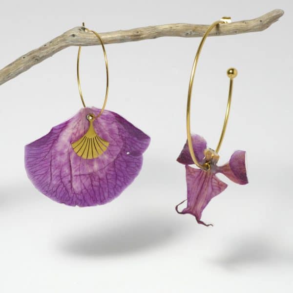Pétale et labelle d'orchidée violette montées en boucles d'oreilles asymétriques sur des anneaux dorés.