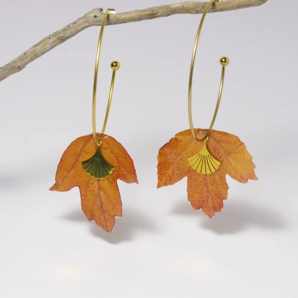 Petites feuilles rousses de viorne montées en boucles d'oreilles sur de grandes créoles dorées.