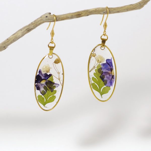 Boucles d'oreilles dont les pendentifs sont des compositions de fleurs et fougères incluses dans de la résine transparente, à l'intérieur d'un fin cadre doré ovale.