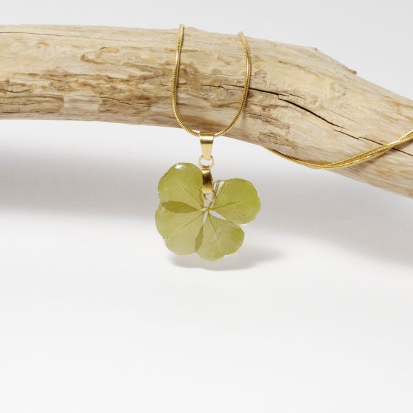 Un vrai petit trèfle à quatre feuilles glacé à la résine et monté en pendentif sur une fine chaîne dorée.