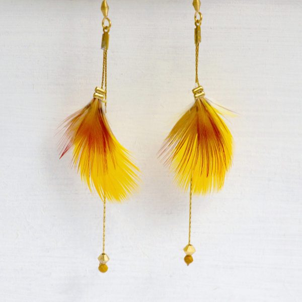 Plumes jaunes et rouges associées à des fines chaînes dorées et des perles de cristal, pour des boucles d'oreilles originales et féminines.