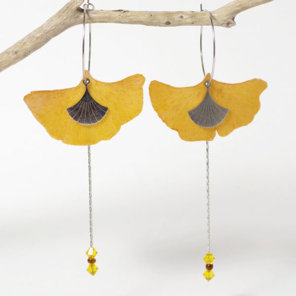 De vraies feuilles de ginkgo biloba sur de fines créoles accompagnées de chaînes dans une composition élancée