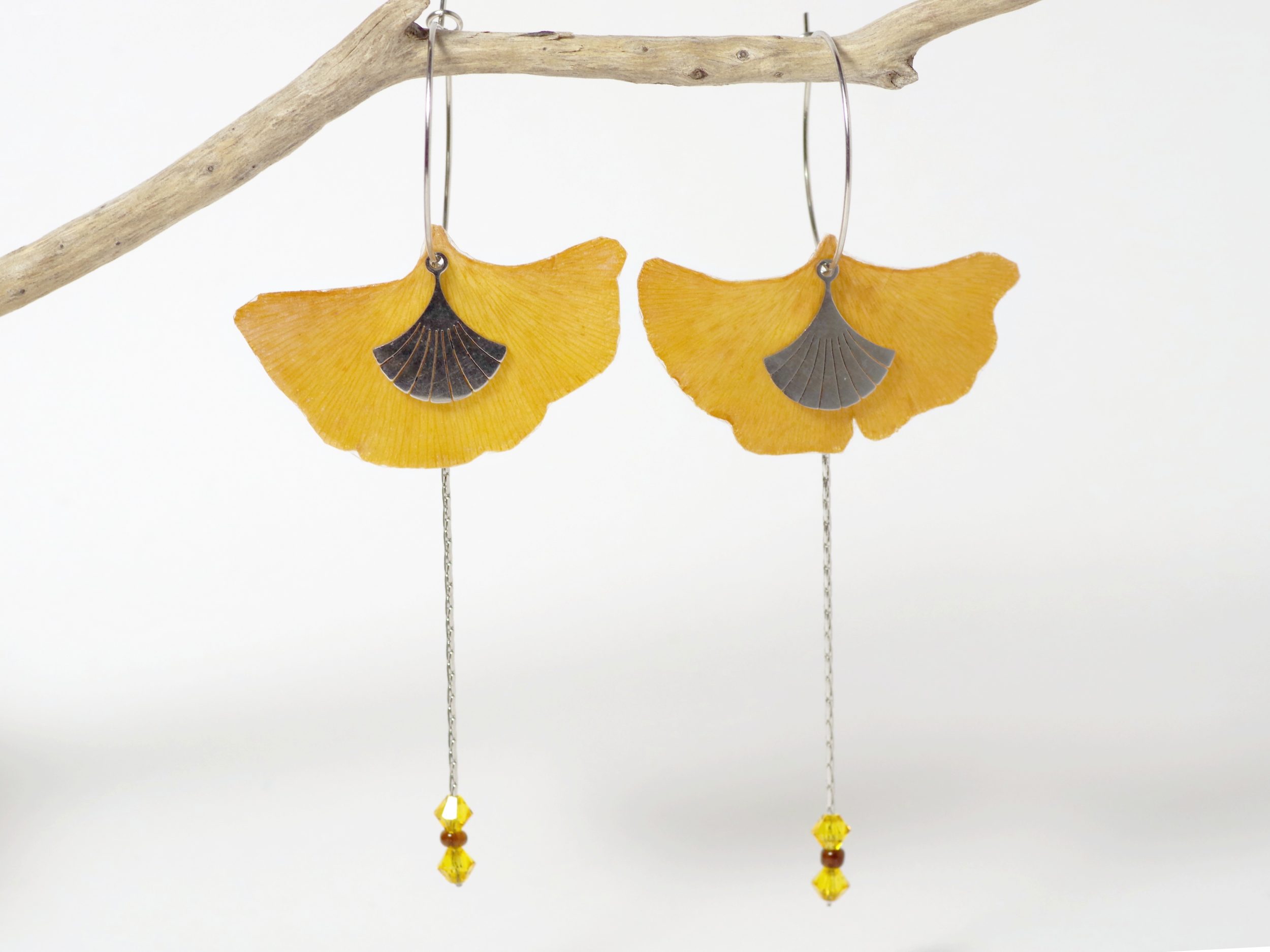 De vraies feuilles de ginkgo biloba sur de fines créoles accompagnées de chaînes dans une composition élancée