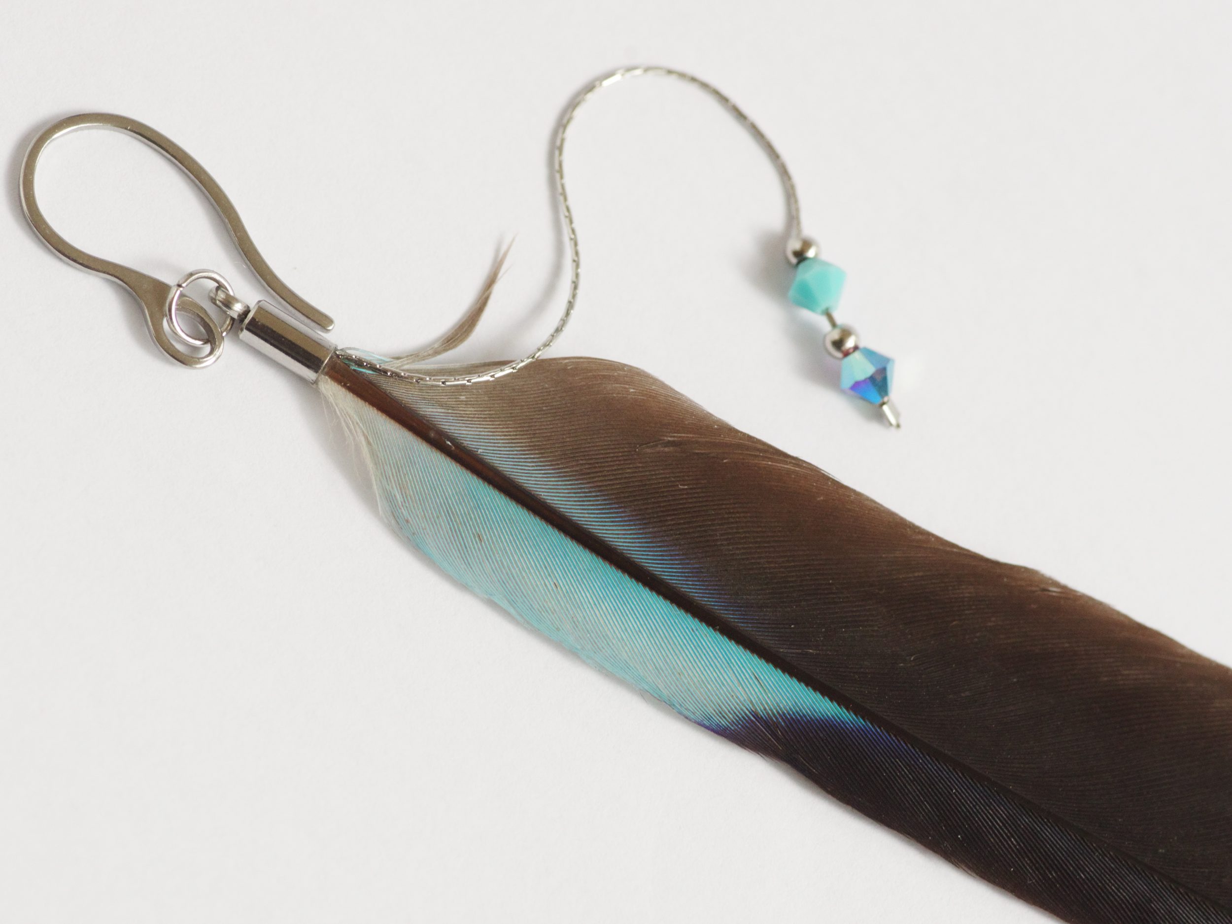 Boucle d'oreille réalisée avec une grande plume noire et bleue et des perles assorties