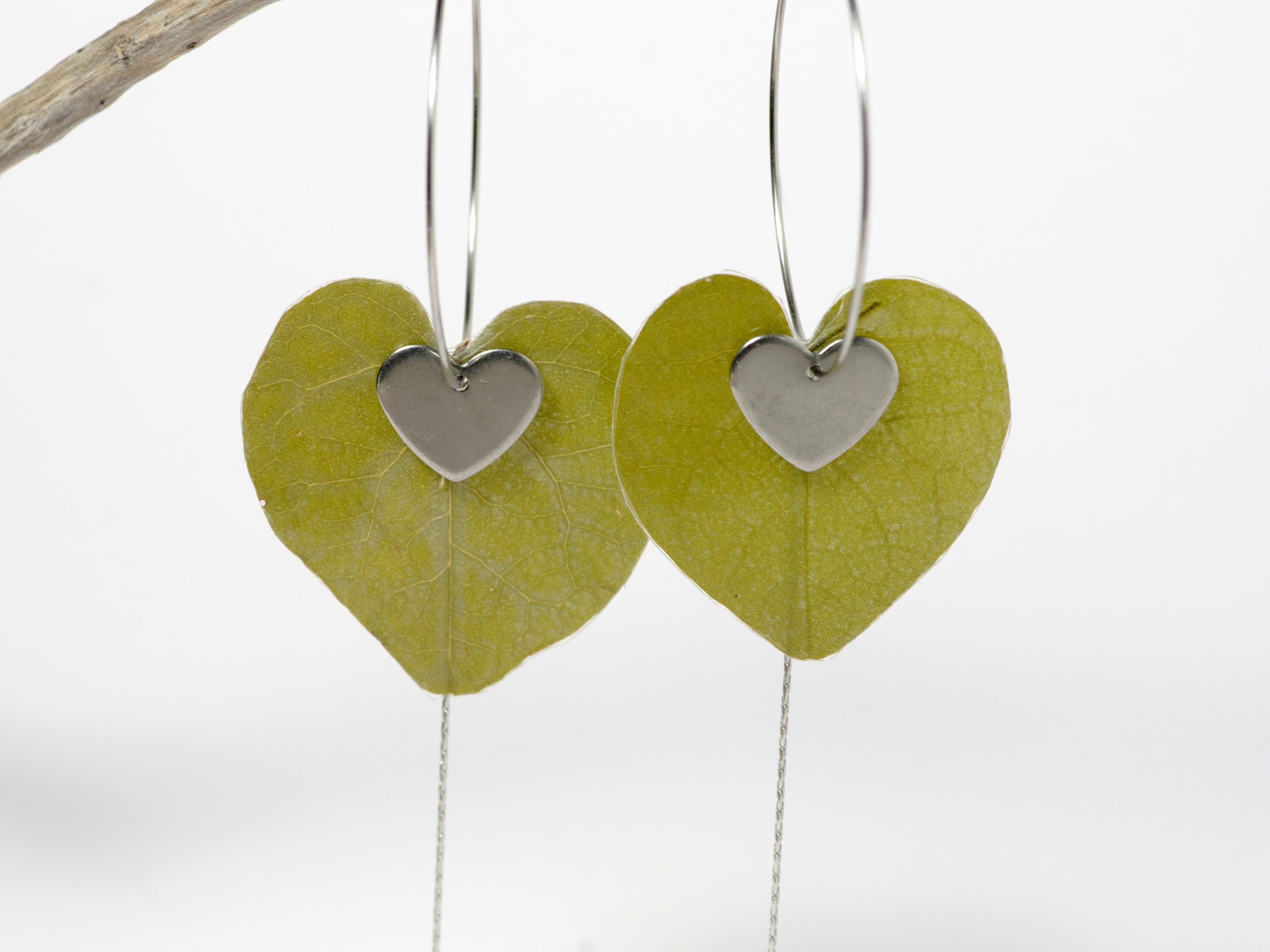 Des feuilles en forme de cœur sur des créoles en inox accompagnées de fines chaînes et cœurs.