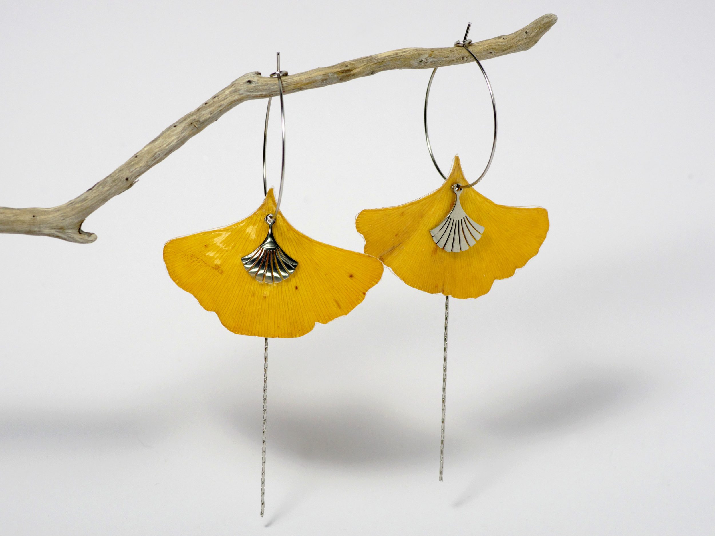 Boucles d'oreilles réalisées avec des vraies feuilles de ginkgo biloba jaune ocre en forme d'éventail. Les feuilles sont enfilées sur des créoles.