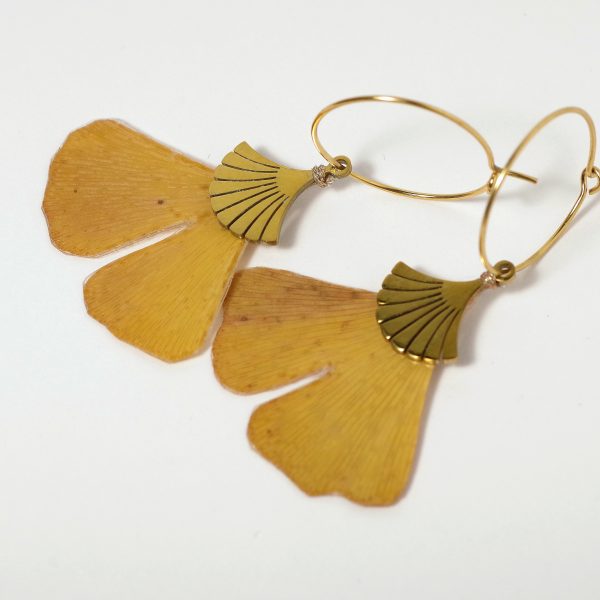 feuilles de ginkgo biloba montées en pendentifs sur des créoles dorées.