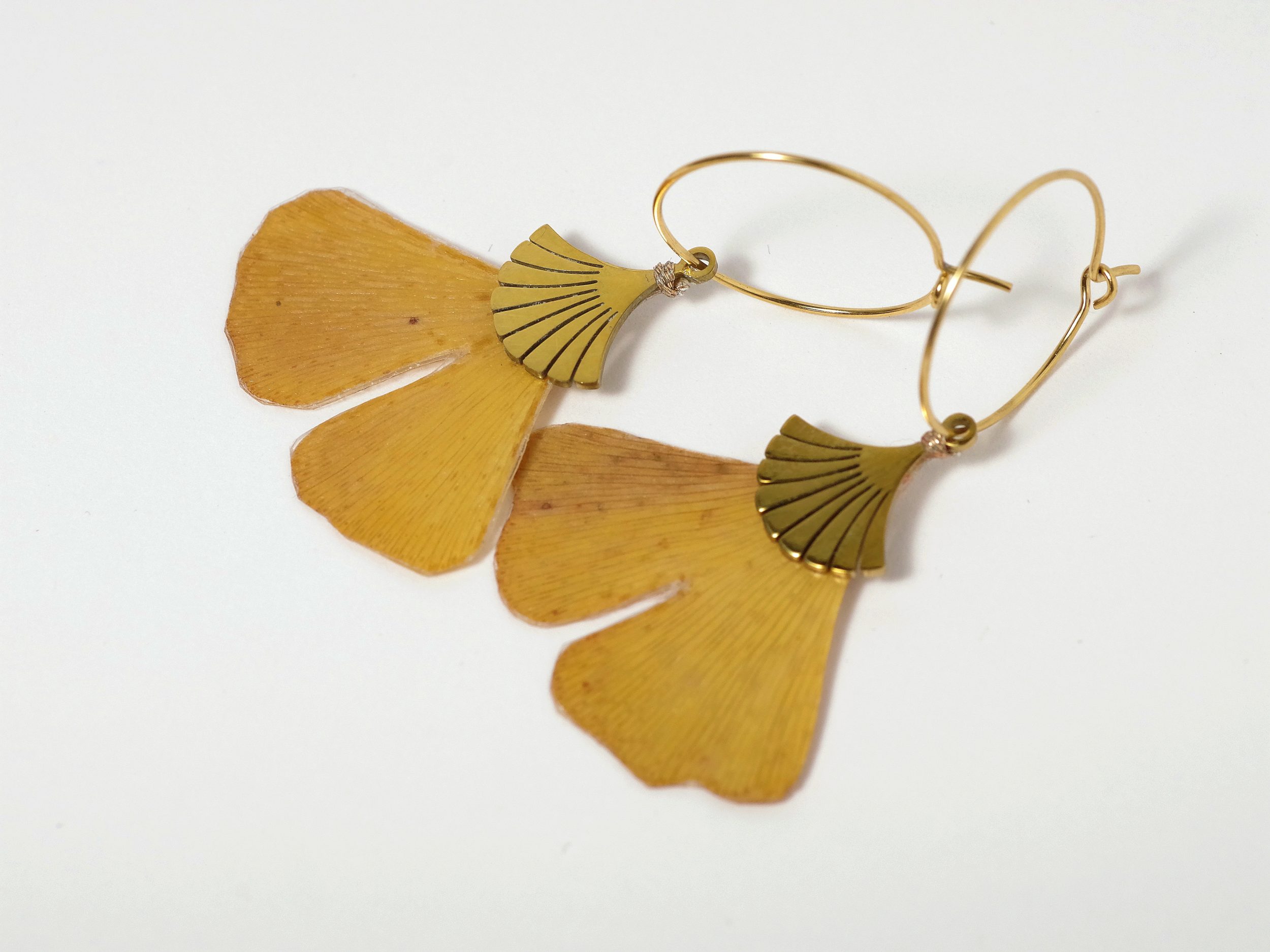 feuilles de ginkgo biloba montées en pendentifs sur des créoles dorées.
