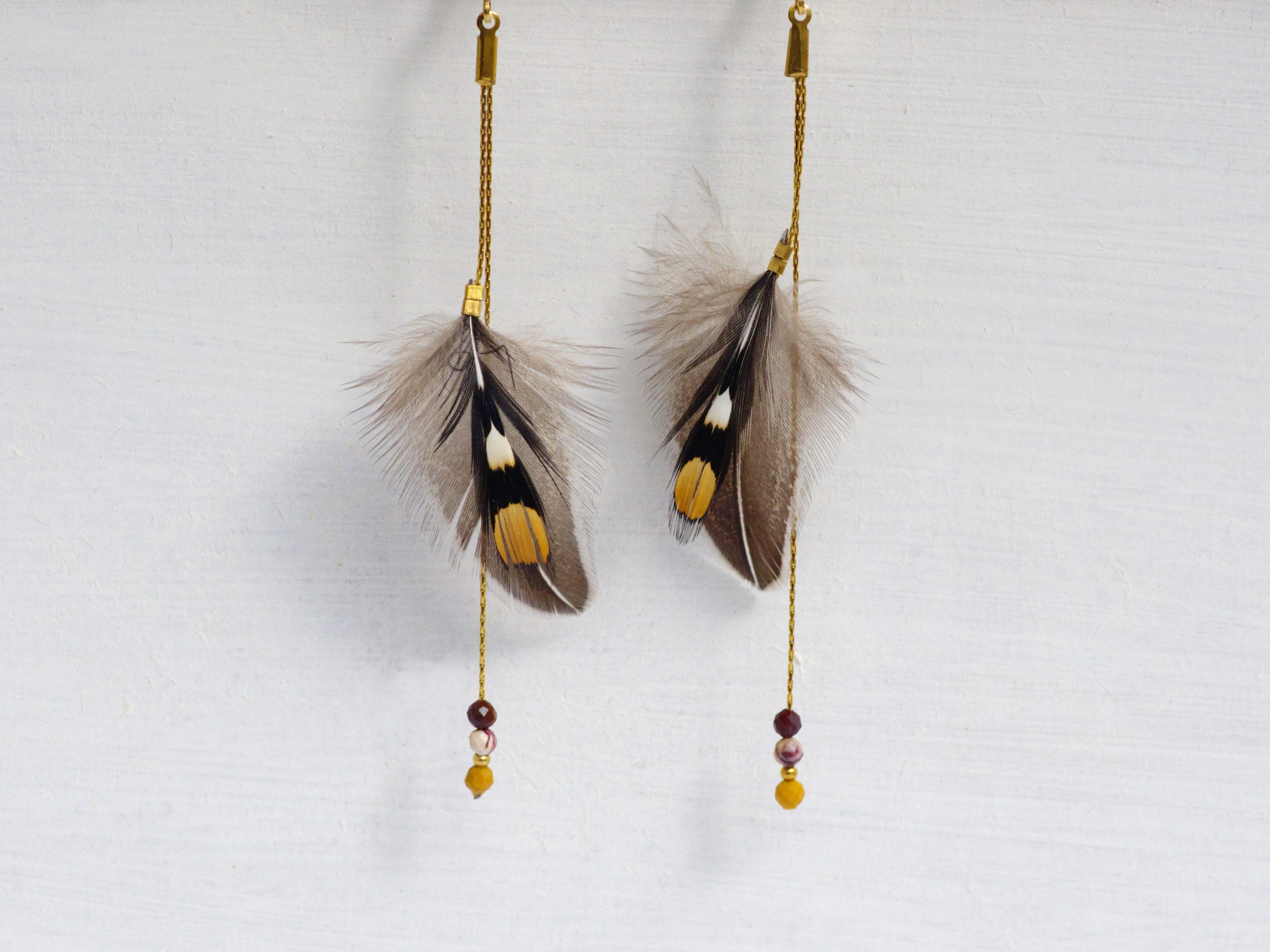 Boucles d'oreilles avec des plumes graphiques de jungle coq (coq de sonnerat) de couleurs : gris noir blanc et ocre.