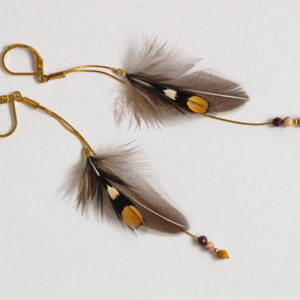 Boucles d'oreilles avec des plumes graphiques de jungle coq sur des fines chaînes dorées. Couleurs : gris noir blanc et ocre (coq de sonnerat).