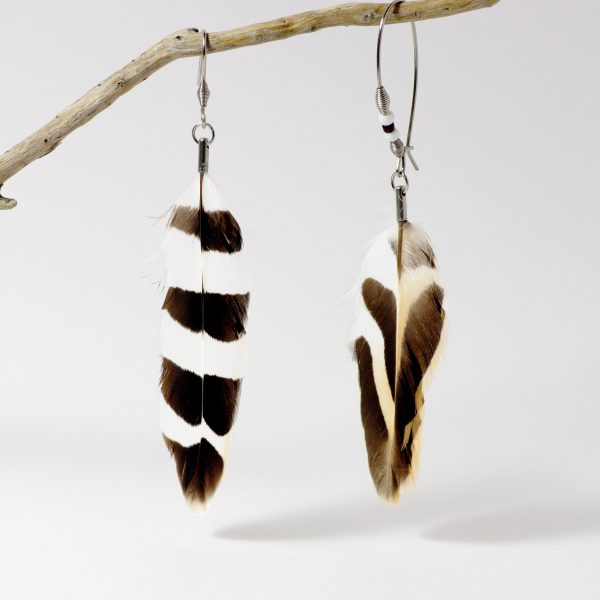 Des boucles d'oreilles asymétriques avec des plumes de huppe fasciée. Elles sont blanches noires et beige avec des graphismes différents.