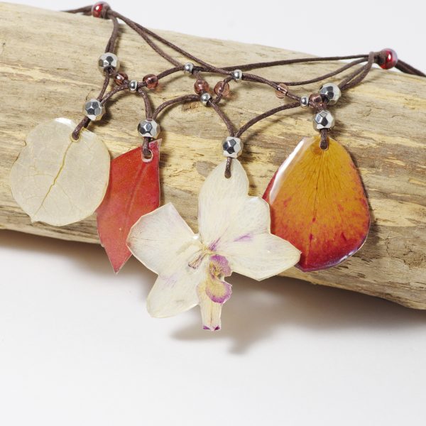 Collier fleuri de style bohème avec une orchidée et des pétales et feuilles dans des tons rouge blanc et rose pâle.