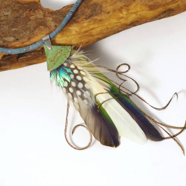 Pendentif réalisé avec une composition de plumes bleu-vert, sur un lacet de liège.