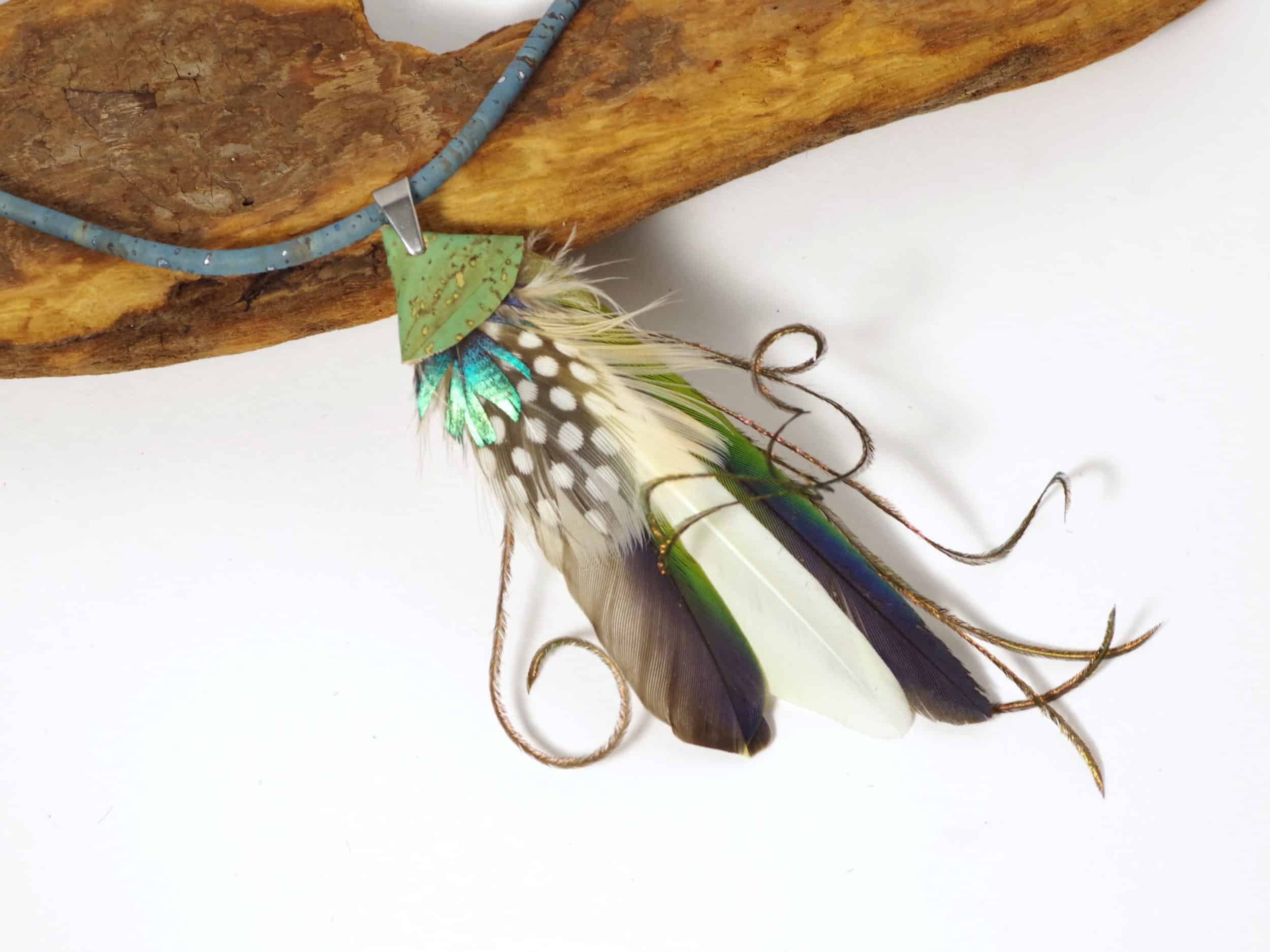 Pendentif réalisé avec une composition de plumes bleu-vert, sur un lacet de liège.