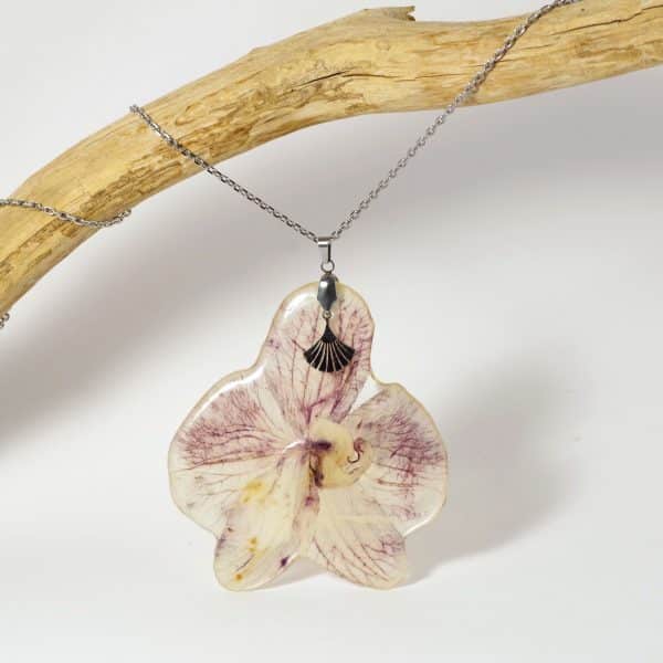 pendentif orchidée cristallisée violette, sur une chaîne en inox, accompagnée d'une petite feuille de ginkgo stylisée