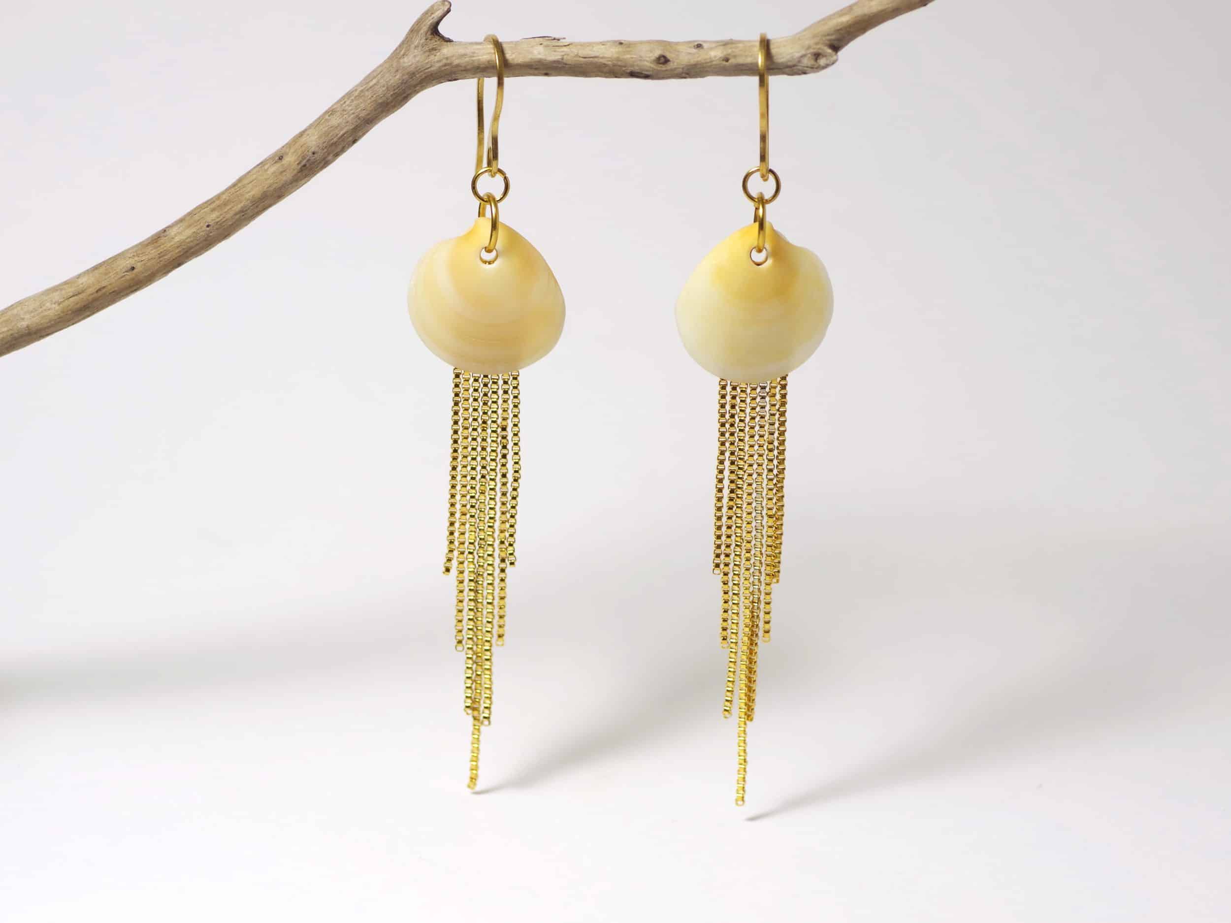 Boucles d'oreilles réalisées avec des coquillages jaunes et des chaînes dorées en cascade.