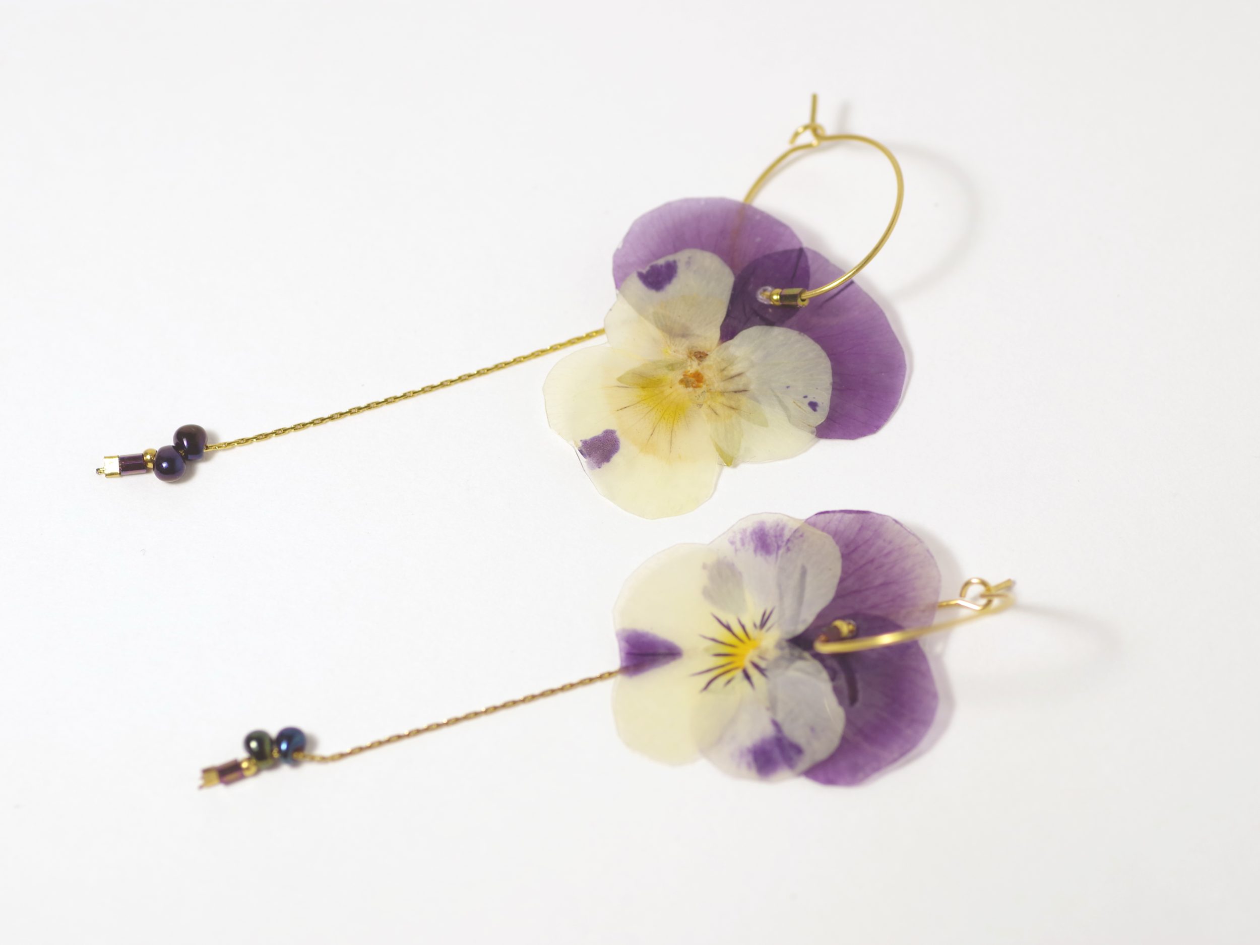 Pensées violet et blanc sur des petites créoles avec des chaînes dorées.