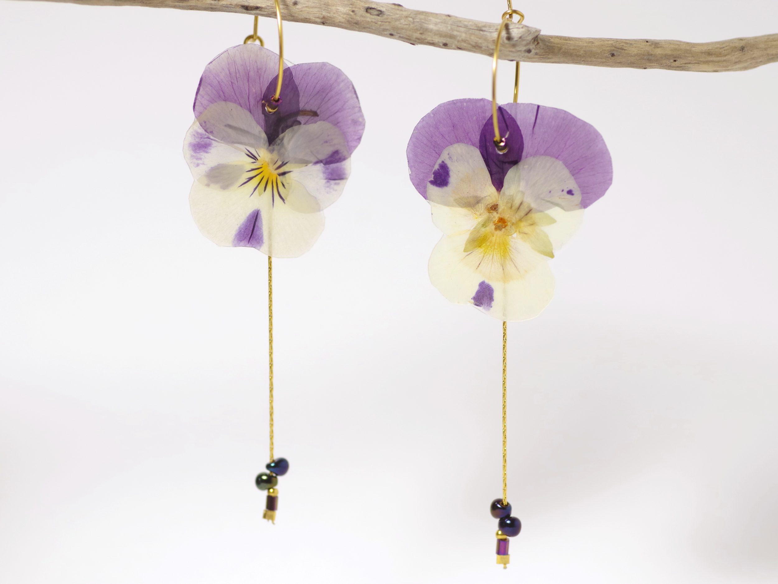 Pensées violet et blanc sur des petites créoles avec des chaînes dorées.