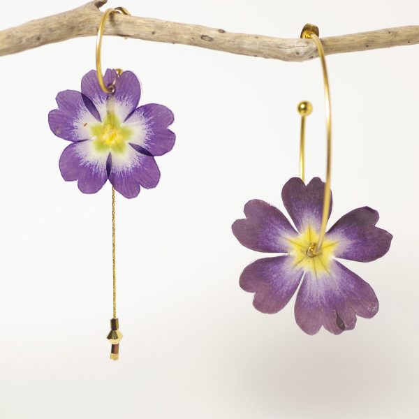 Belles primevères violettes et jaunes sur des créoles asymétriques dorées.